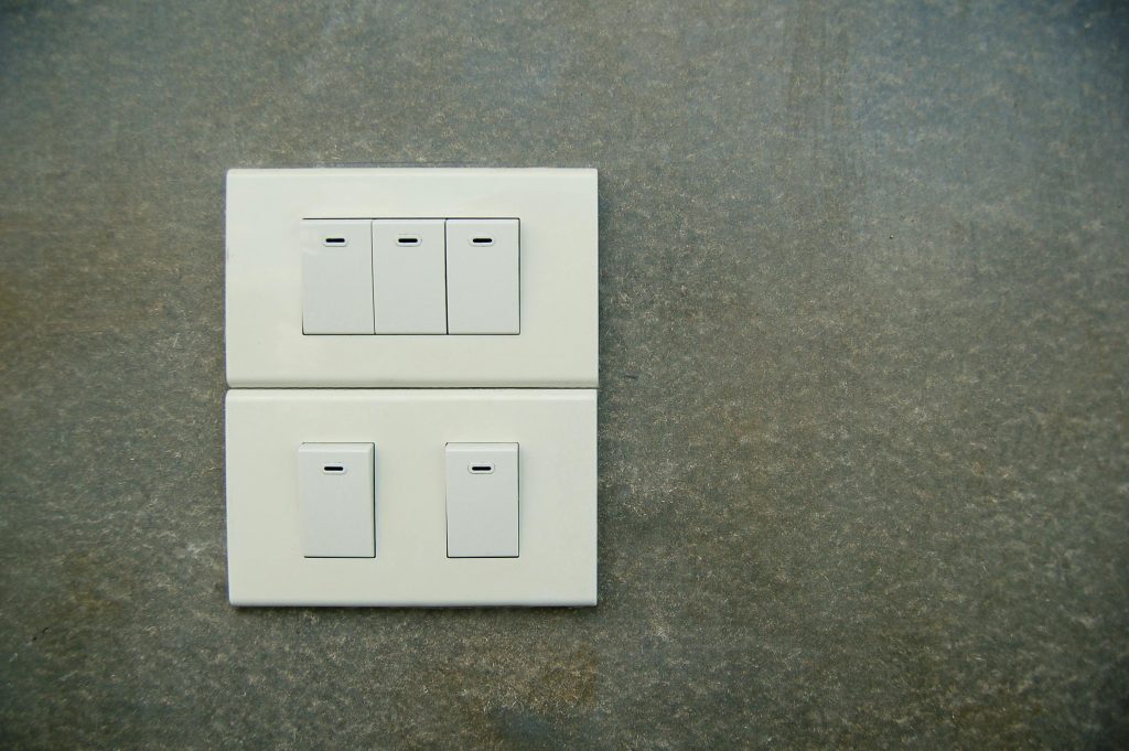 Minimalist photo of white electrical rocker switches on a textured stone wall background.